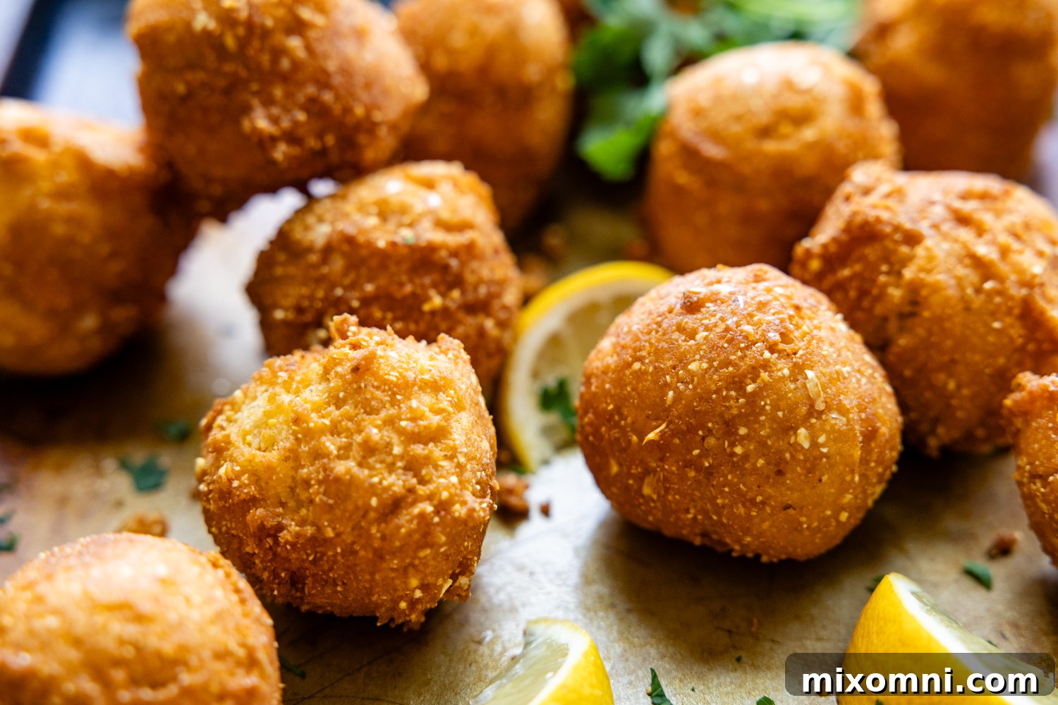 Hush puppies and lemon wedges on a serving dish.