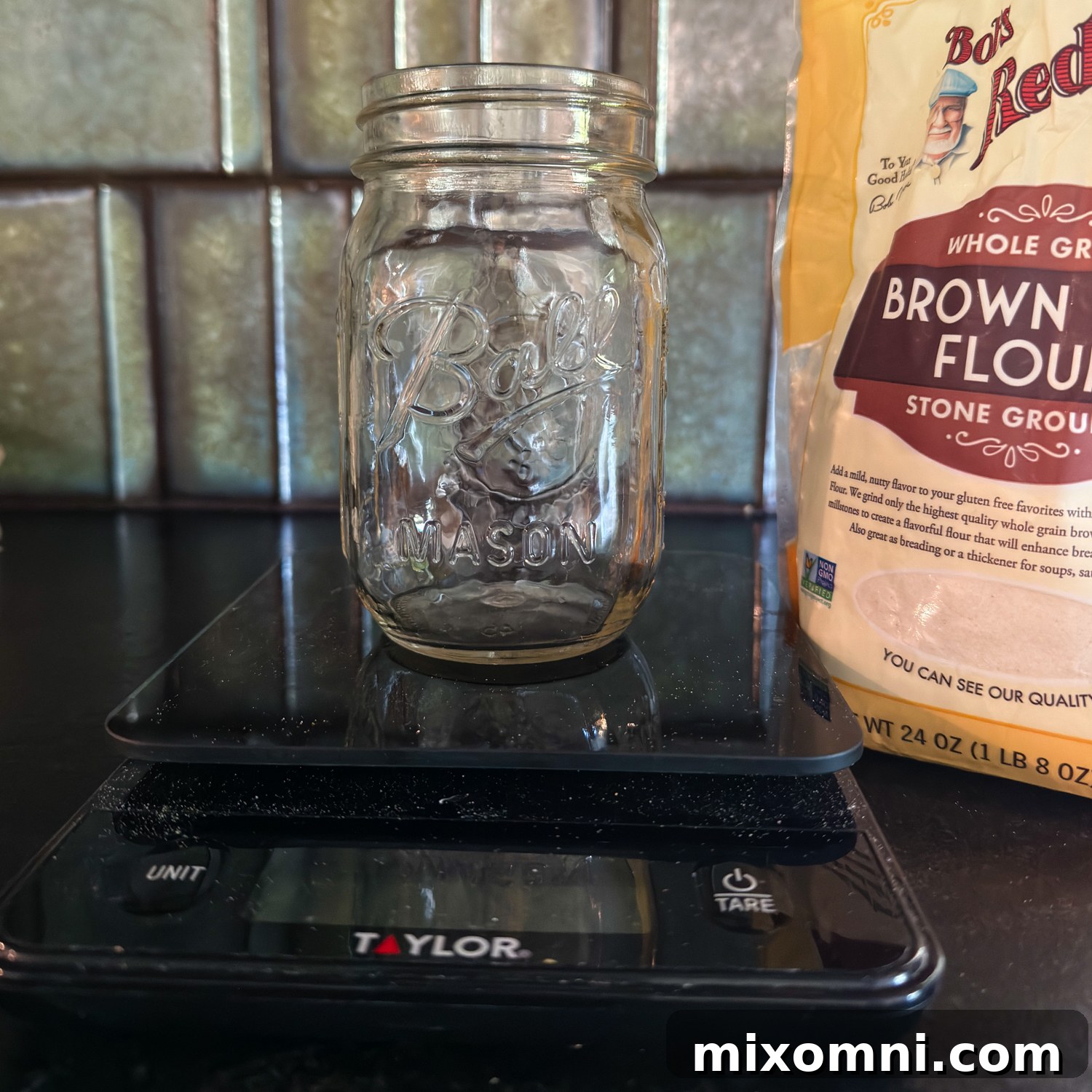 an empty glass jar on a scale with brown rice flour in the background.