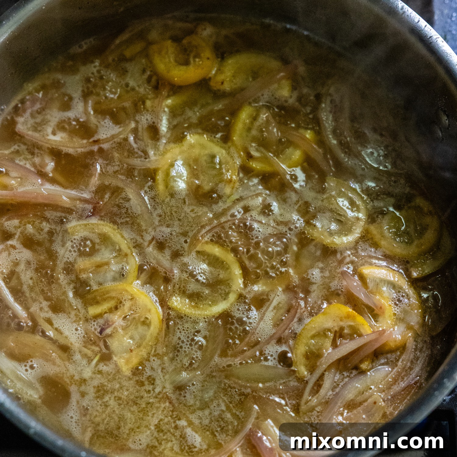 Wine added to stock pan with sautéed shallots and lemon slices.